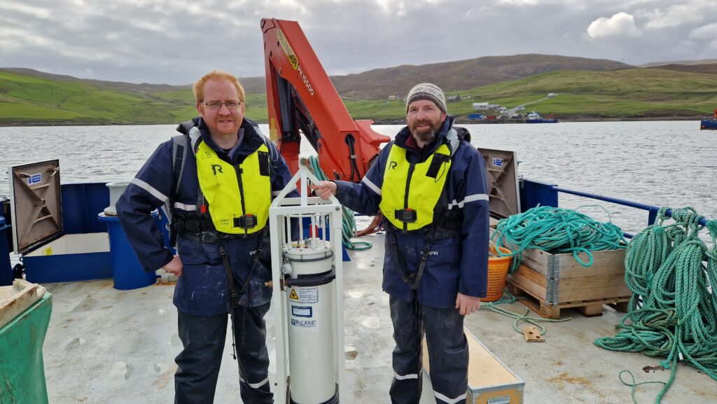 Two men standing on either side of an underwater sensor device