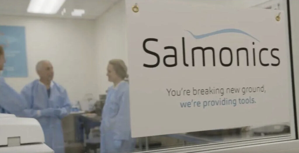 Scientists next to Salmonics sign