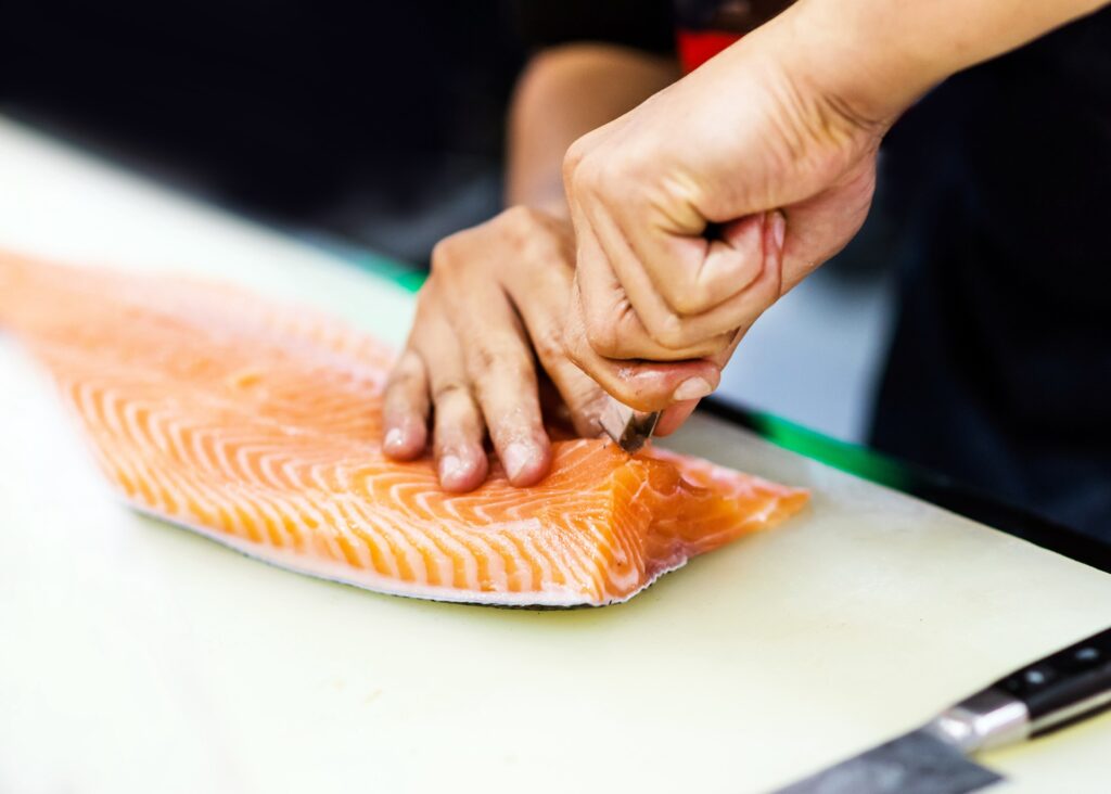 chef using a knife to slice salmon fillet