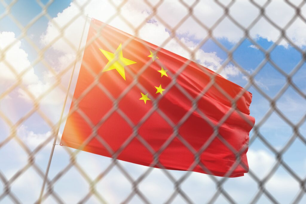 A steel mesh against the background of a blue sky and a flagpole with the flag of china